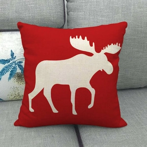 Red linen star pillowcase with white reindeer silhouette on a modern grey fabric sofa
