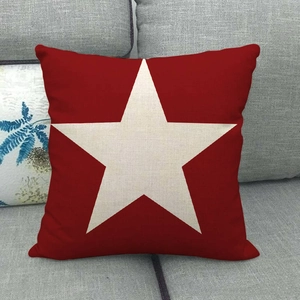 Close-up of red linen pillowcase featuring a large cream star on a grey sofa background
