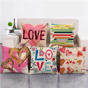 Detail showing five linen pillow covers with pink heart and LOVE prints on a sofa