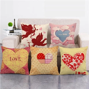 Set of five linen heart cushions with LOVE prints displayed on a cozy sofa