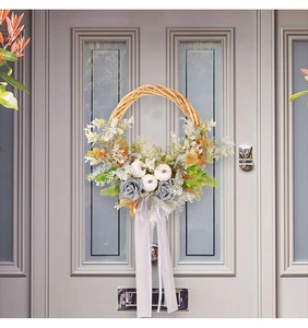 Gros plan d'une couronne de citrouilles avec roses grises et rubans sur une porte blanche