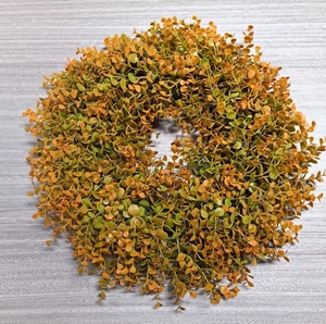 Detailed top view of autumn eucalyptus wreath with orange and green leaves on wood