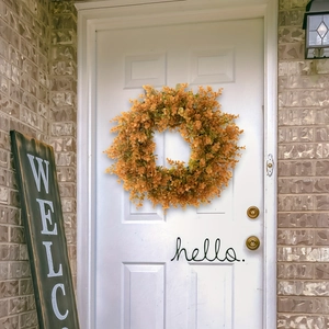 Autumn eucalyptus wreath with orange and yellow leaves hanging on a white front door