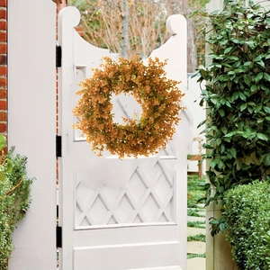Detailed view of autumn eucalyptus wreath featuring vibrant orange and yellow leaves on white door
