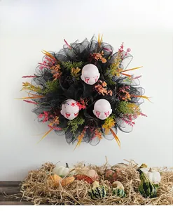 Macro detail of Halloween wreath with bloody doll heads and black mesh on a white wall