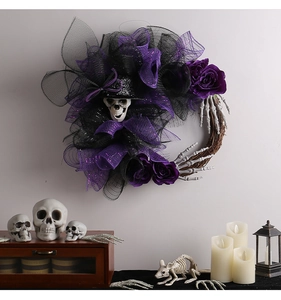 Couronne d'Halloween avec crâne, roses violettes et bras de squelette sur un mur gris