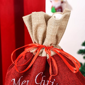 Detail of burlap Christmas gift bag with Merry Christmas embroidery and red silk ribbon