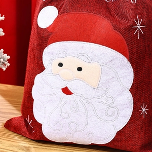 Close-up of red linen Christmas gift bag with Santa Claus felt patch and snowflake embroidery