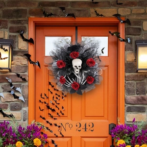 Halloween wreath with white skull, red roses, and skeleton hands on an orange door