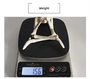 Détail d'une décoration de squelette en résine pesant 156g sur une balance pour Halloween