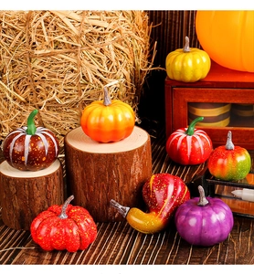 Close-up of assorted faux pumpkins and gourds on rustic wood for harvest decor