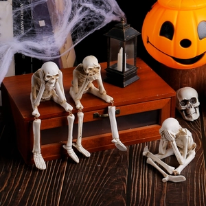 Halloween skeleton resin figurines in 'no evil' poses on festive wooden background