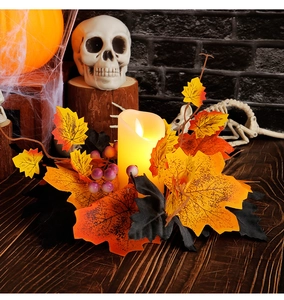 Close-up of Halloween candle wreath with maple leaves, purple berries and warm LED light