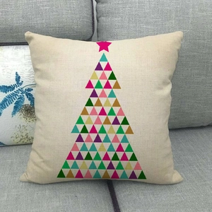 Close-up of linen Christmas pillow case with colorful geometric tree on a grey sofa