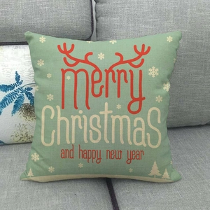 Detail view of green linen Christmas pillow cover with red reindeer antlers and snowflake
