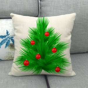 Detail of Christmas tree linen pillowcase on a grey sofa with red ball ornaments