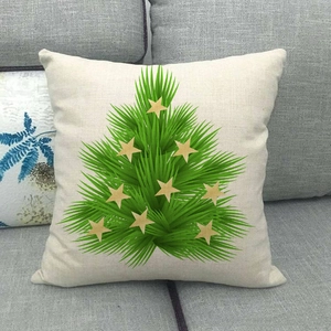 Detail of linen pillowcase with green palm leaf Christmas tree and gold stars on gray sofa