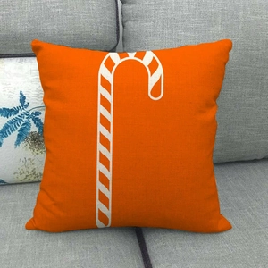 Linen Christmas pillow case with orange candy cane pattern on a dark grey sofa