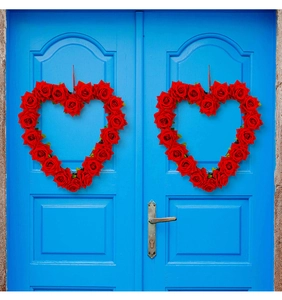 Set van twee rode kunstmatige rozen hartkransen hangend aan een blauwe houten deur