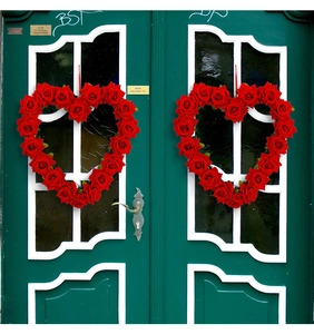 Detail van twee hartvormige rode rozenkransen hangend aan een deur voor bruiloftsdecor