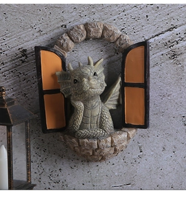 Dettaglio di una statuetta di drago in resina che spunta da un arco di finestra in pietra