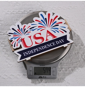 Detail showing wooden Independence Day USA table sign being weighed on a digital scale