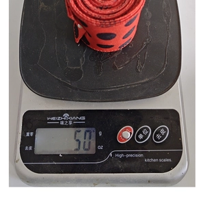 Detail shot of a 50g roll of red ribbon with black polka dots on a digital scale