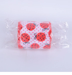 Detail of ladybug and polka dot printed ribbon roll in clear packaging for decor