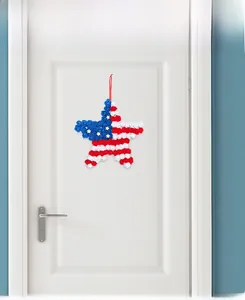 Patriotic star wreath with red white and blue flowers hanging on a white wooden door