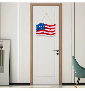 Detail of USA flag door wreath made of faux roses hanging on a white wooden door