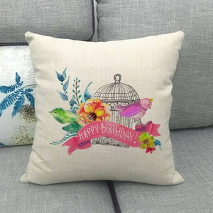 Linen square cushion cover with watercolor birdcage and Happy Birthday print on grey sofa