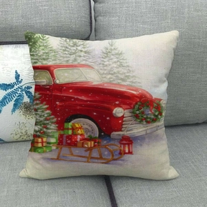 Christmas linen pillow cover featuring a vintage red truck and sled on a sofa