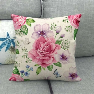 Close-up of floral linen cushion cover with pink roses and butterflies on a grey sofa
