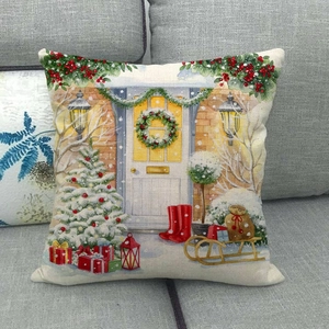 Close-up of linen Christmas pillow cover featuring a snowy cottage scene on a sofa