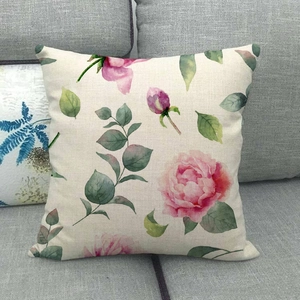 Linen square throw pillow cover with pink watercolor floral rose pattern on grey sofa