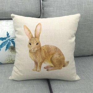 Detail of linen cushion cover showing textured beige fabric and printed rabbit design