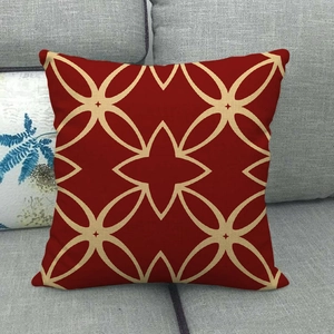Detail van een rode kussenhoes met beige stermotieven op een grijze bank