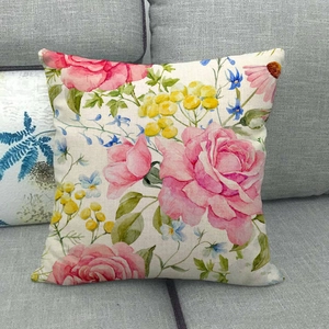Detail of linen cushion cover featuring watercolor flower patterns on a grey fabric sofa