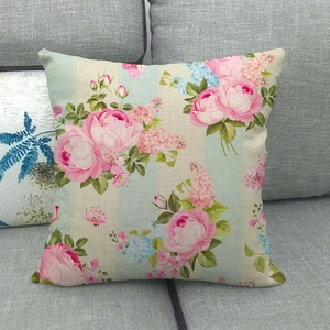 Detail of floral linen cushion cover with pink roses on blue striped fabric on a sofa