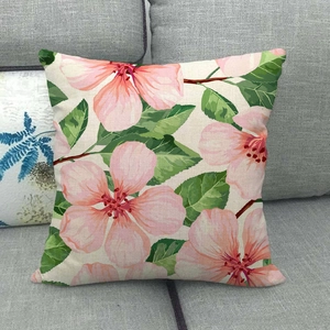 Close-up of linen cushion cover with pink floral patterns on a gray sofa