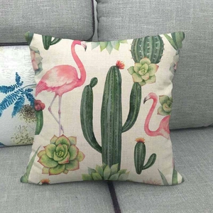 Housse de coussin en lin avec motif cactus et flamant rose sur un canapé gris