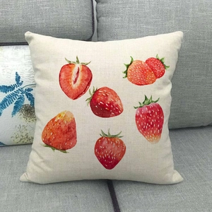 Linen cushion cover with vibrant watercolor strawberry print on a gray sofa