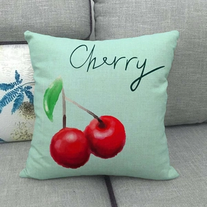 Close-up of linen cushion with realistic cherry illustration on a grey fabric sofa
