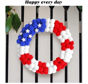 Detail van de USA Independence Day krans met rood wit en blauwe pompons op wit hekwerk