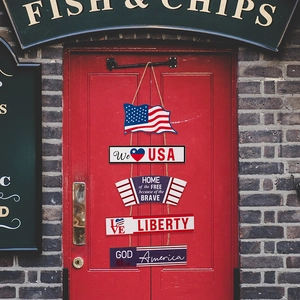 Close-up of five-tier patriotic USA wooden door sign hanging on a red rustic door