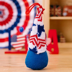 Close-up of a knitted USA gnome ornament with stars and stripes on a rustic wooden desk