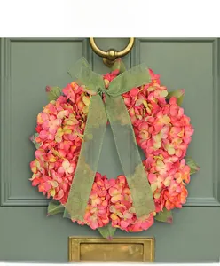 Detail of autumn hydrangea wreath with green bow on dark door for festive home decor