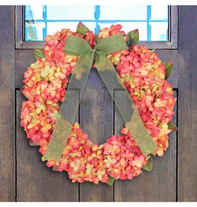 Detail of pink hydrangea wreath with green burlap bow on dark wooden door background