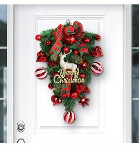 Detail of Christmas wreath with white reindeer model and red bows on a white door