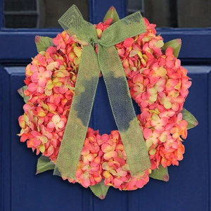 Autumn hydrangea wreath with orange petals and green ribbon on a dark blue door